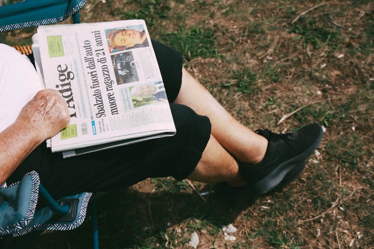 persona sentado sujetando periodico