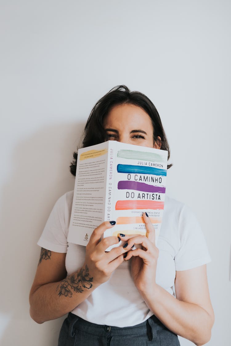 mujer sujetando libro cubriendo la cara