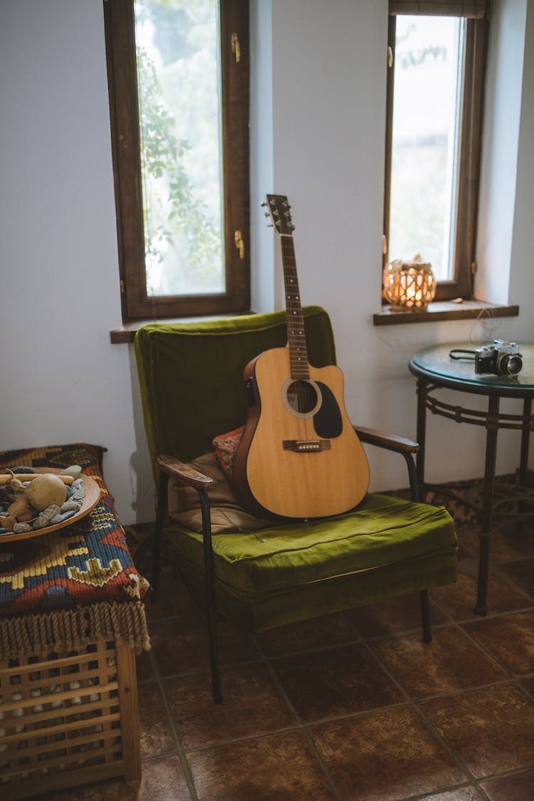 guitarra acustica marron en silla