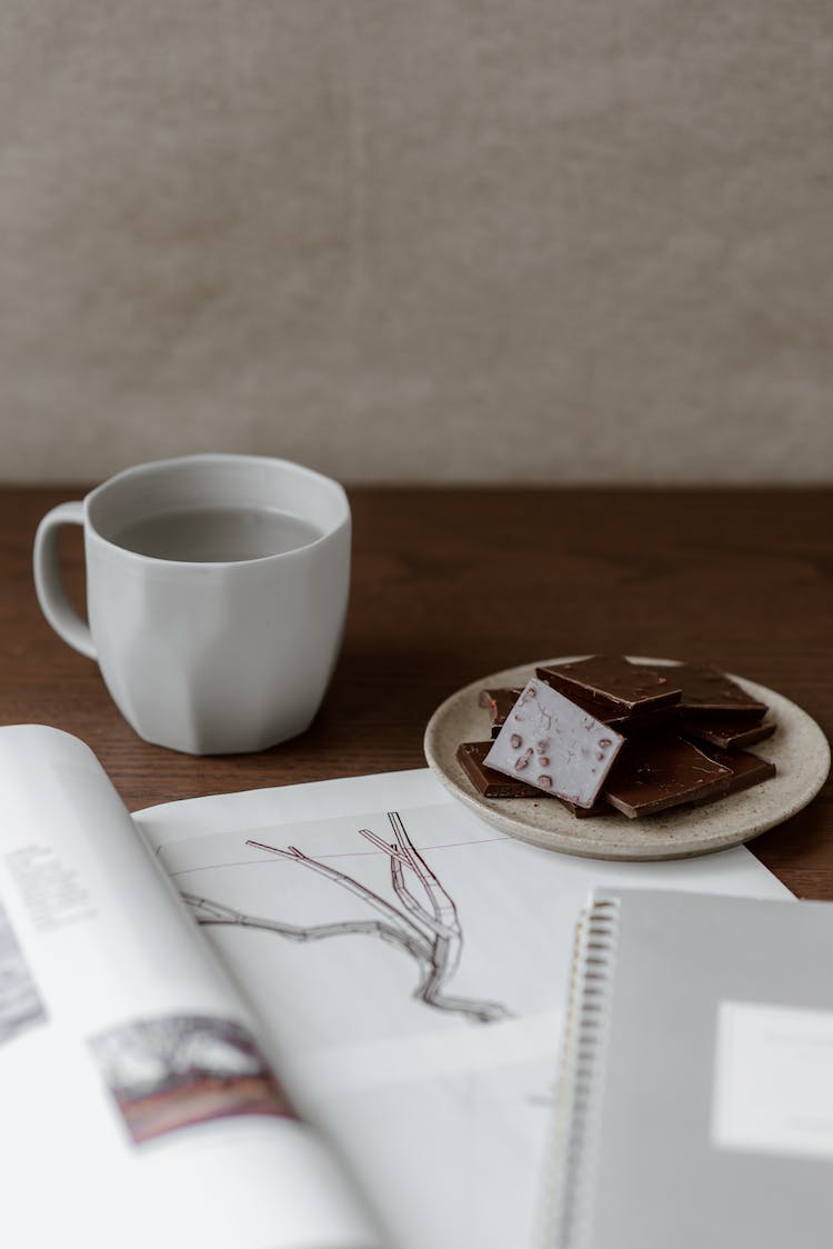 chocolate con leche cerca de cuaderno y taza