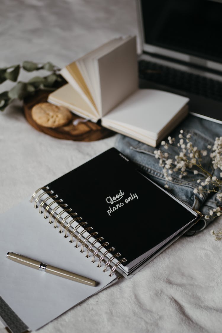 cuaderno negro al lado del lapiz clic blanco