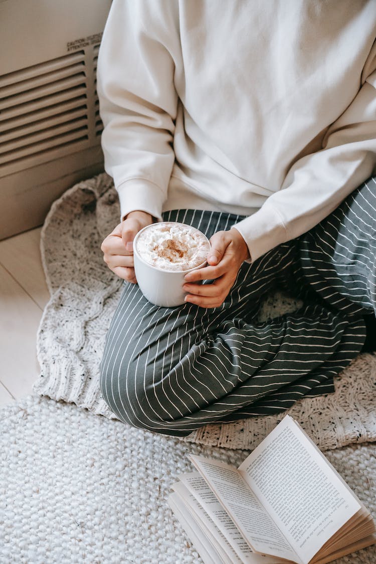 persona en camisa blanca de manga larga con taza de ceramica blanca