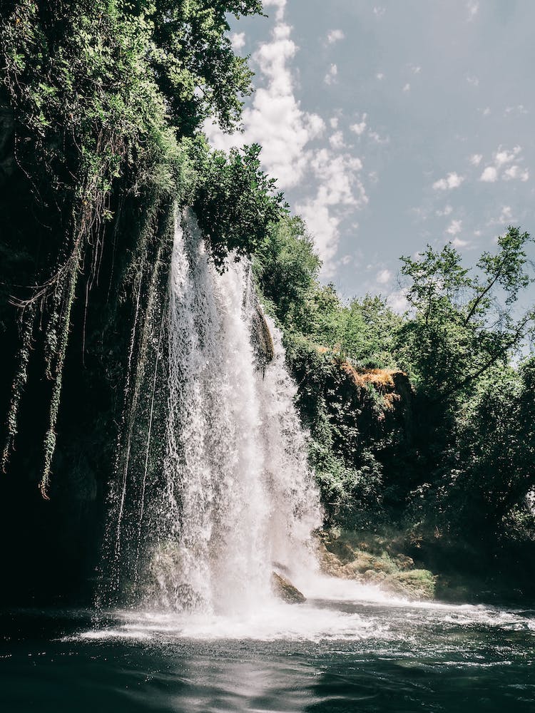 cascadas cerca de arboles verdes bajo un cielo azul