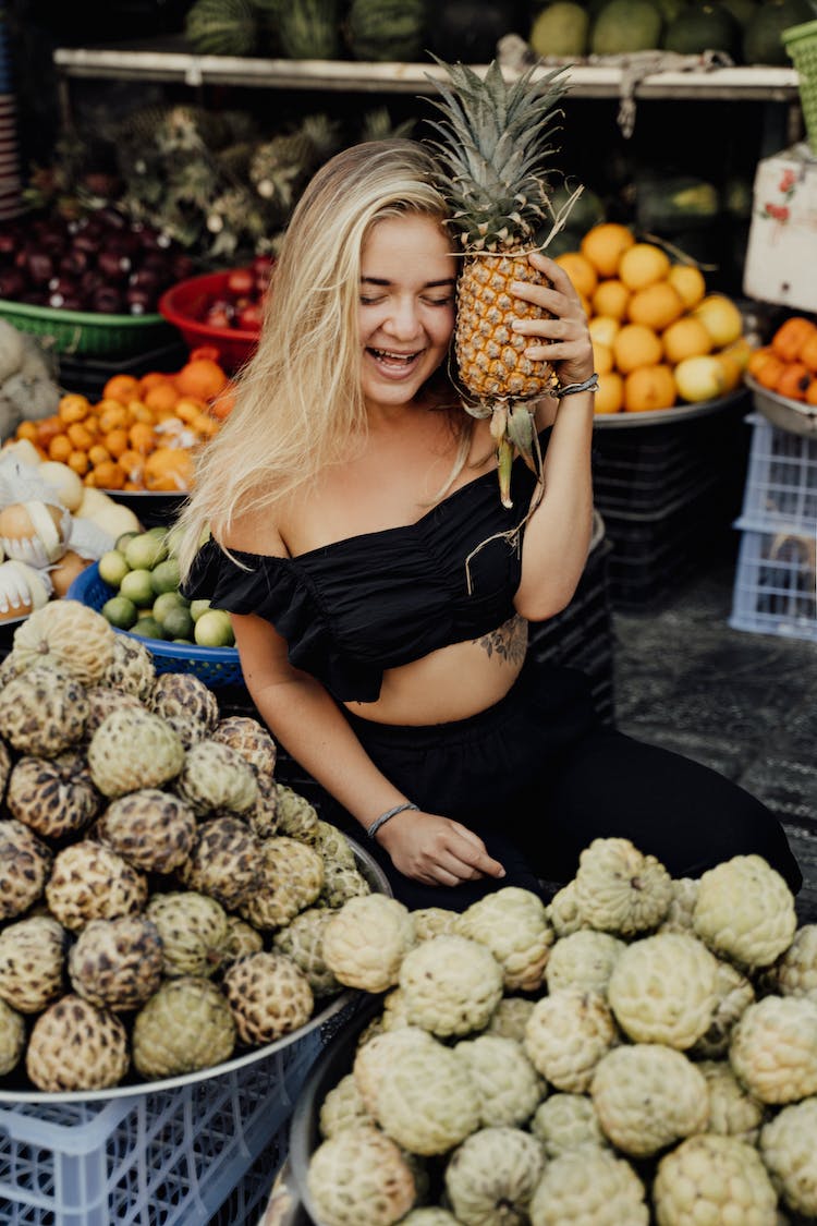 mujer en negro camiseta sin mangas tenencia fruta verde