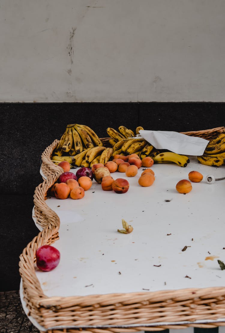 fruta de manzana roja y fruta de platano amarillo en canasta tejida marron