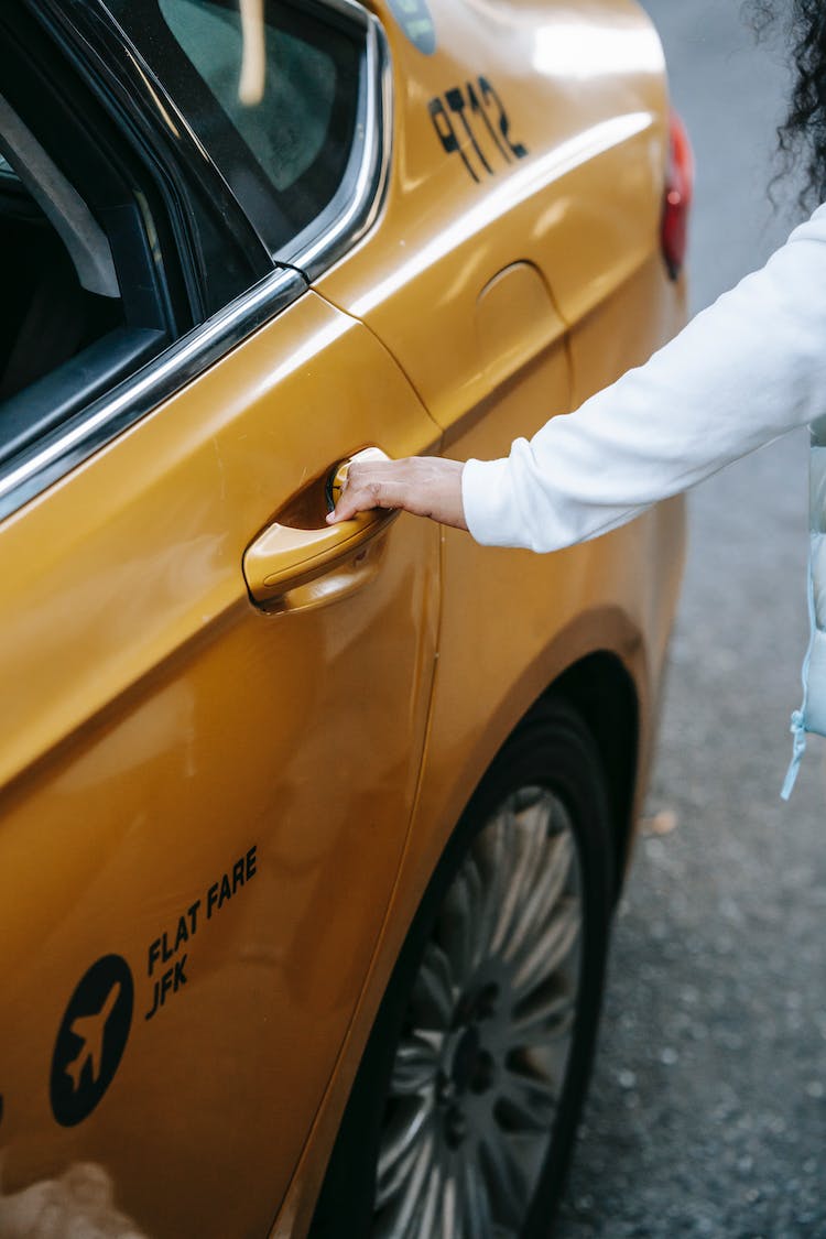 persona en pantalones blancos y zapatos de cuero marron de pie junto al coche amarillo