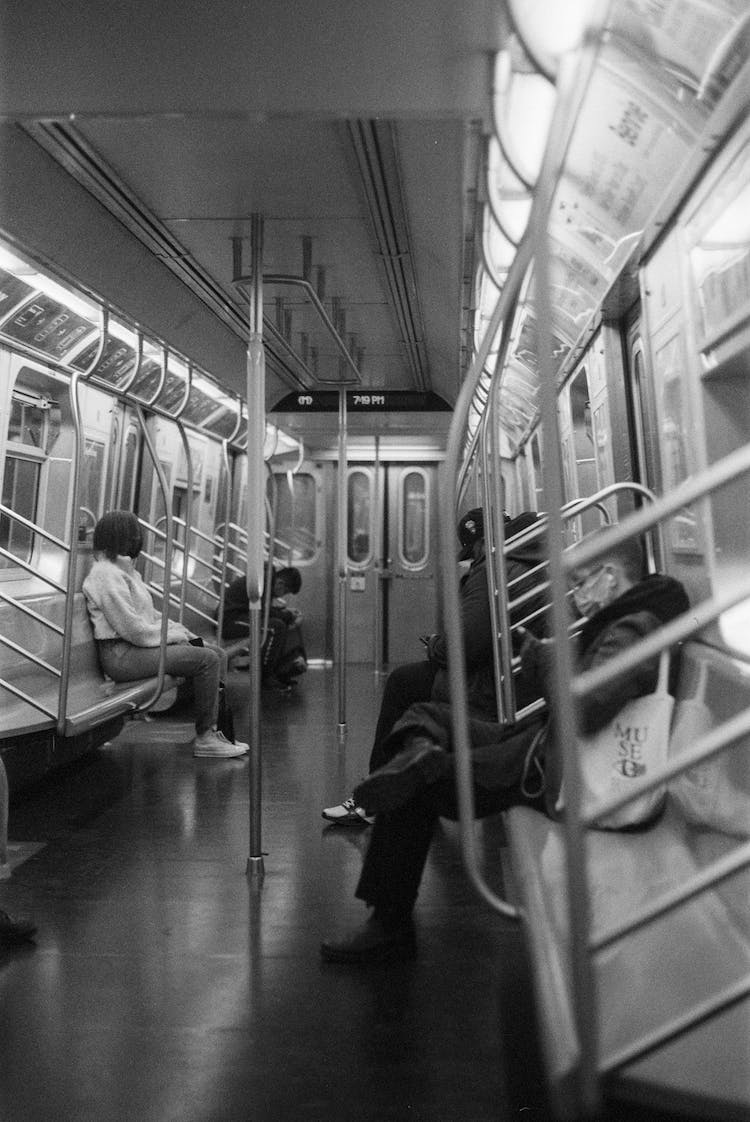 foto en escala de grises de personas sentadas dentro del tren