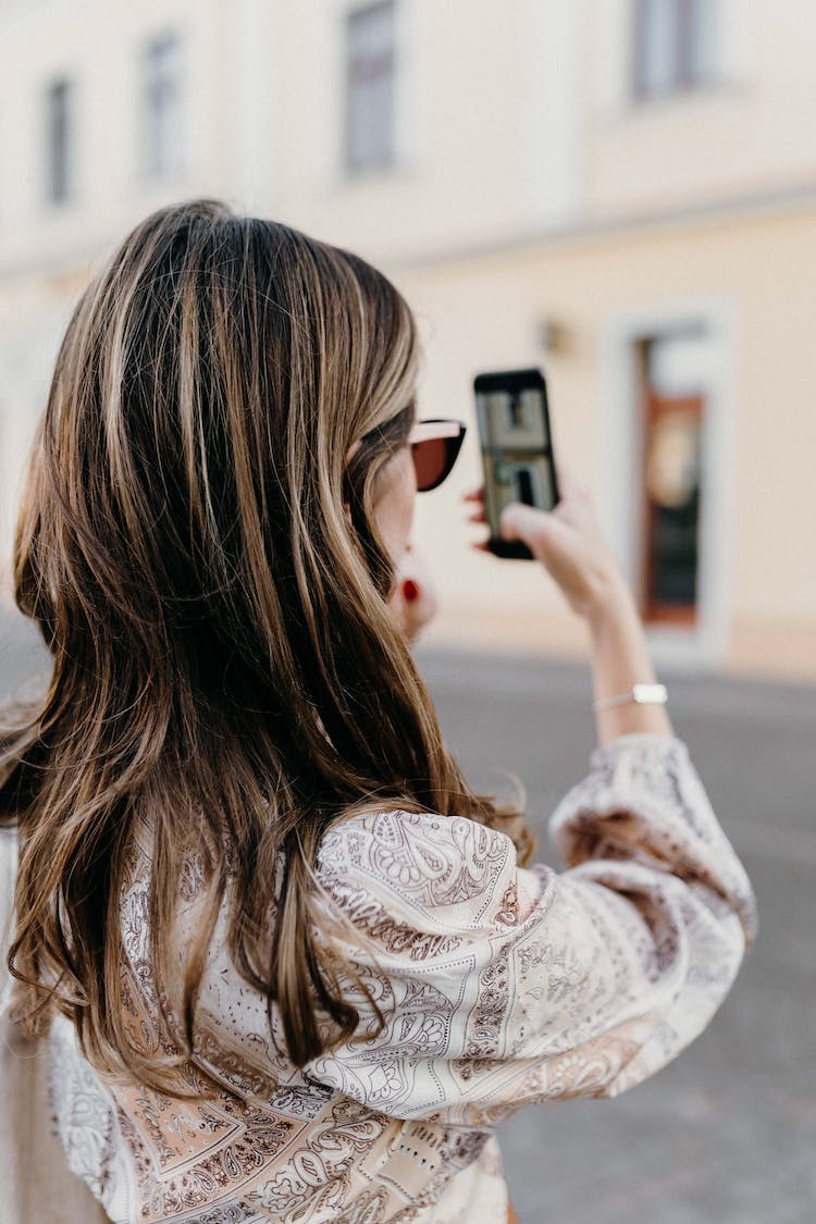 mujer telefono inteligente edificio pelo largo