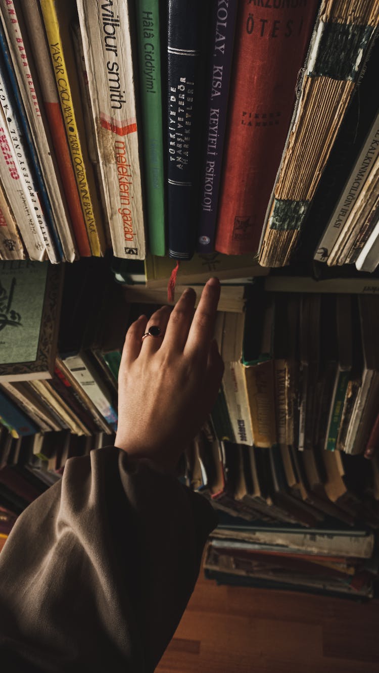 mujer mano libros estante